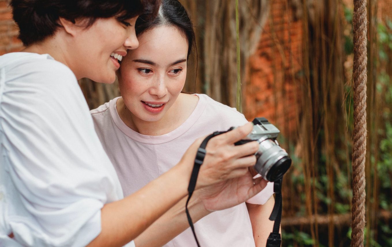 happy asian women looking at screen of photo camera
